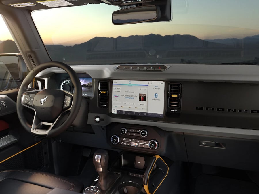 Interior of a modern SUV cockpit with touchscreen display, steering wheel, and dashboard controls at sunset.